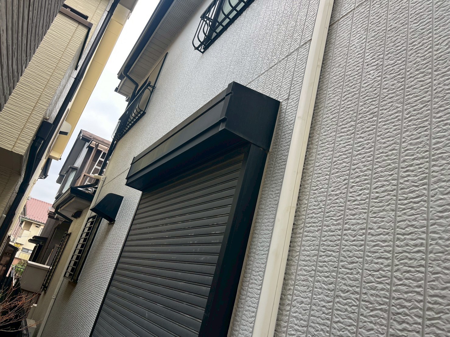 苔の生えたシャッターとグレーの外壁